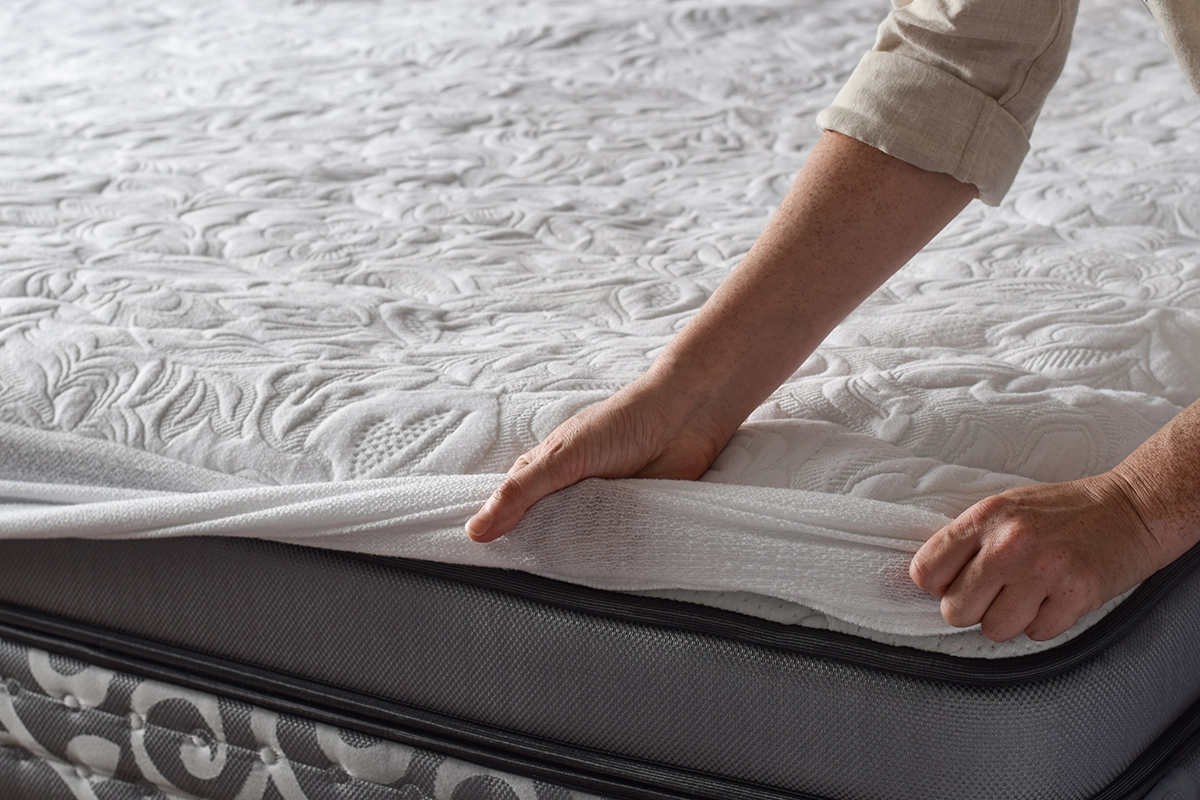 Woman Putting Protective Mattress Pad on - Alaska Pest Management