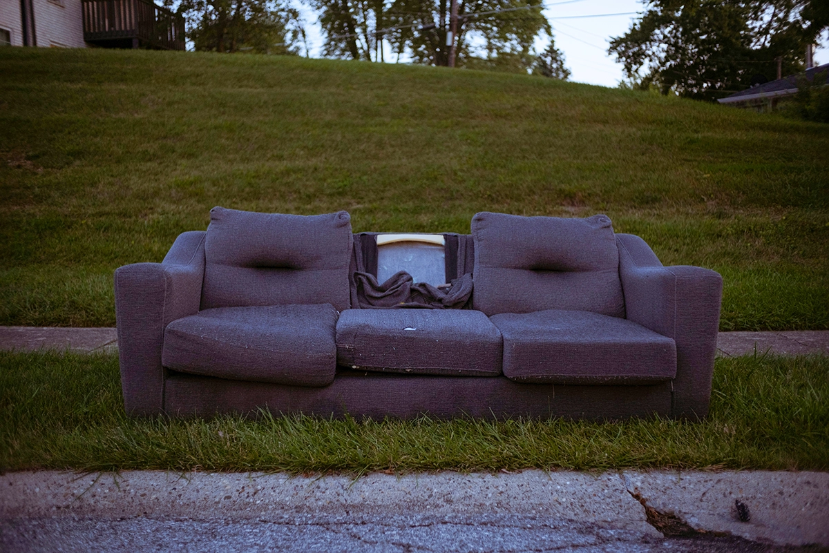 Old abandoned couch left on the curbside, showing the risks of secondhand furniture and potential pest infestations.