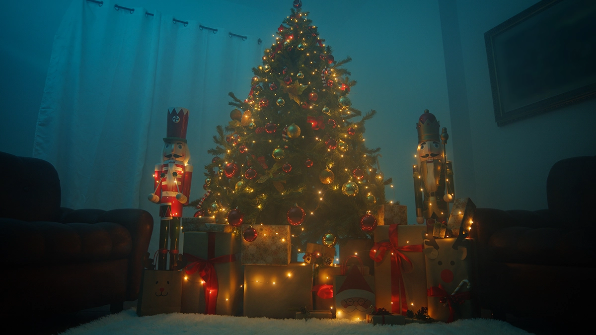 Dimly lit living room with a decorated Christmas tree surrounded by wrapped gifts and nutcracker figures.