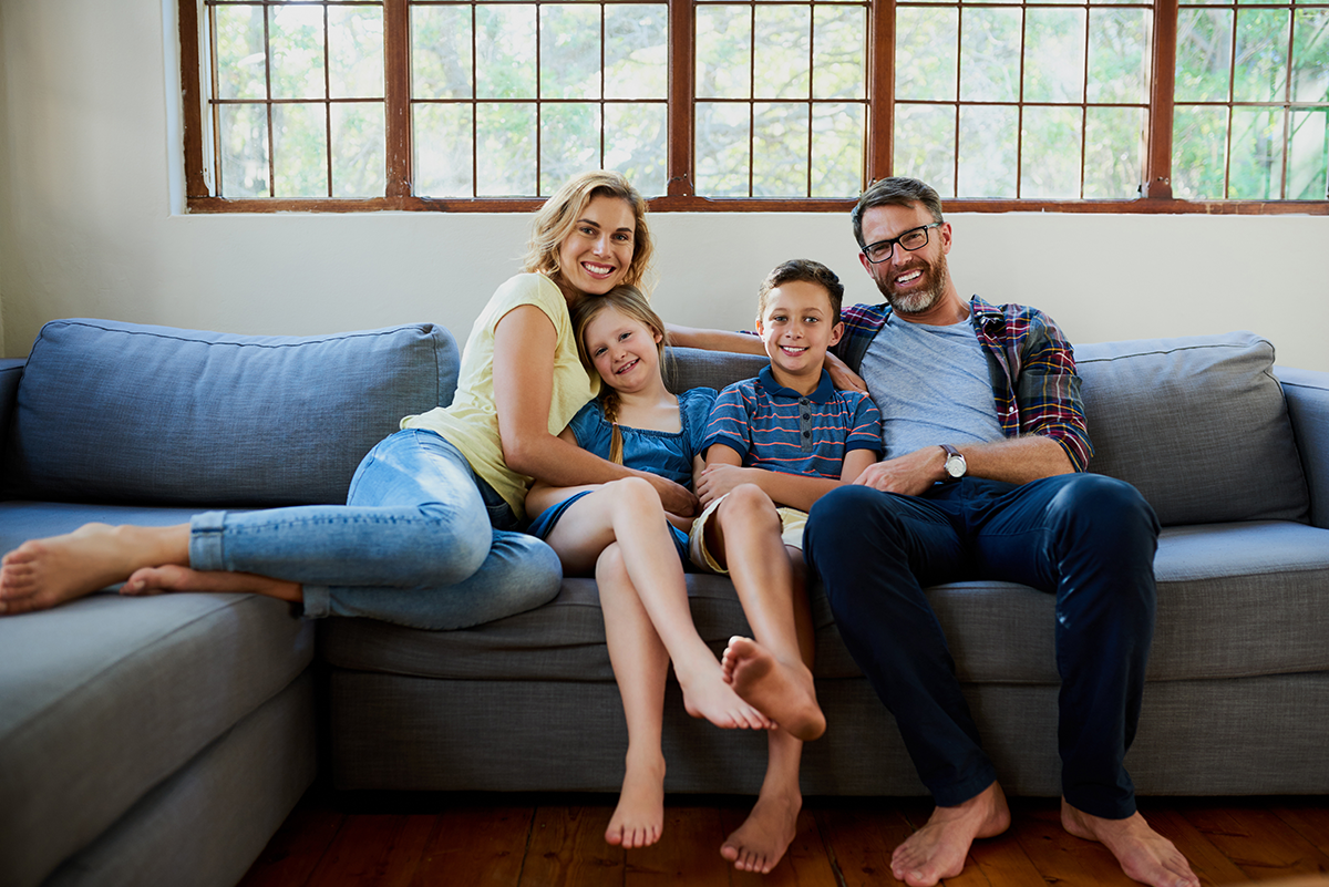 Family relaxing together on a living room couch in a clean, comfortable home.
