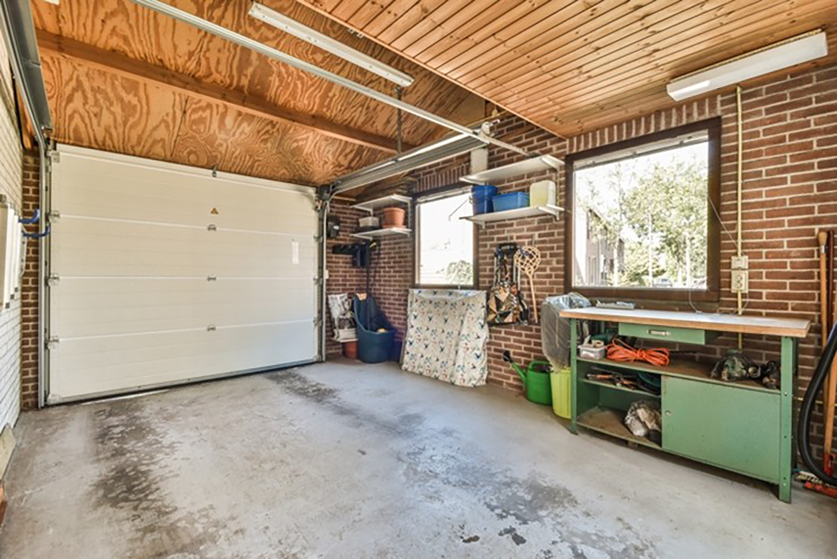 Interior garage space with concrete floor, workbench, shelving, and storage items, showing a clean but accessible storage area.