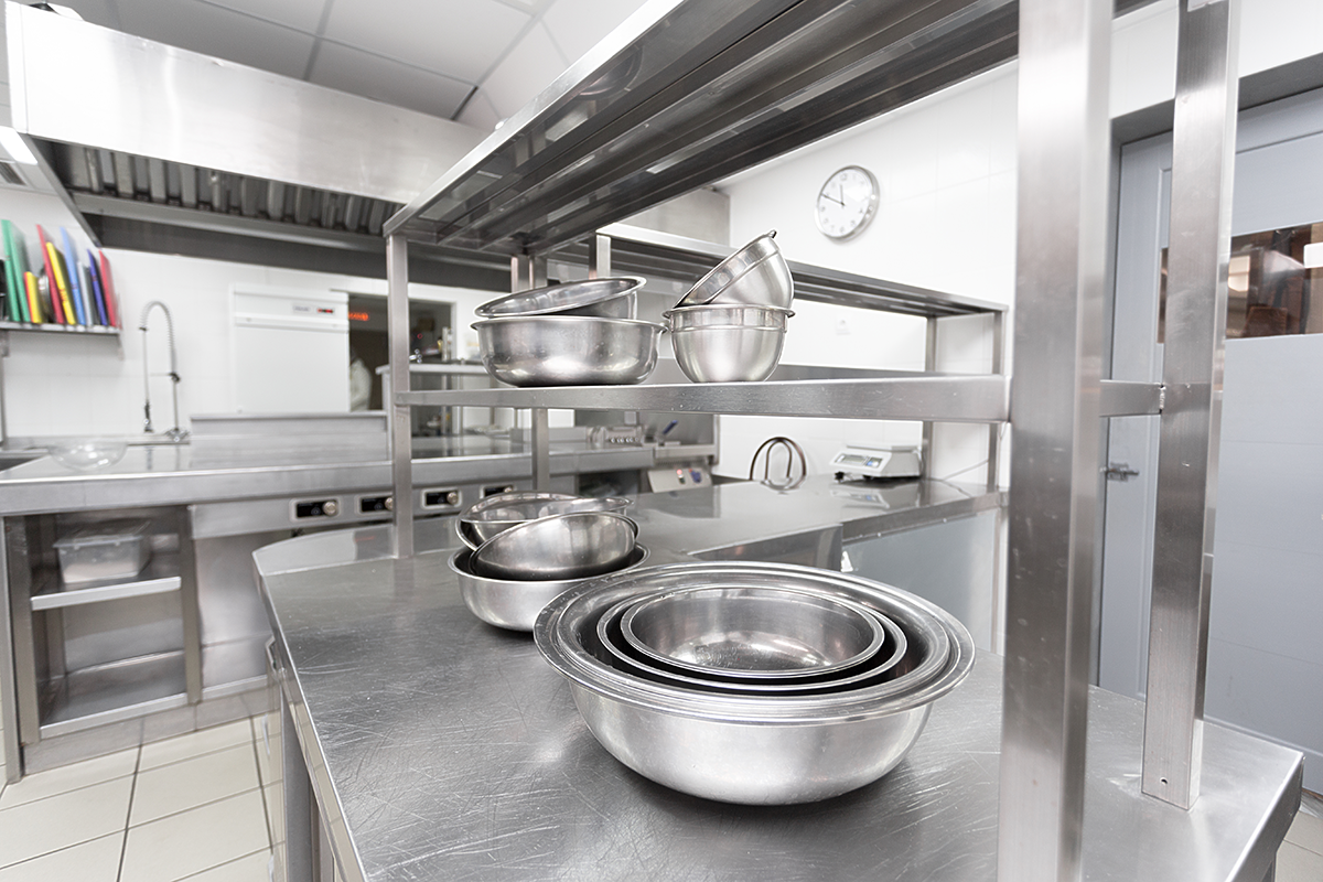 Stainless steel commercial kitchen with metal mixing bowls and professional cooking equipment