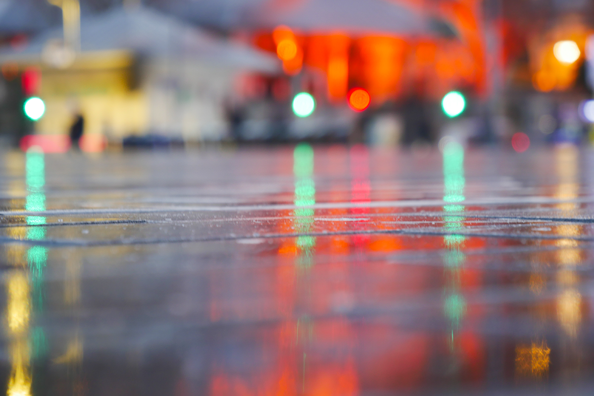 Wet city street at night with colorful traffic light reflections on pavement and blurred urban lights